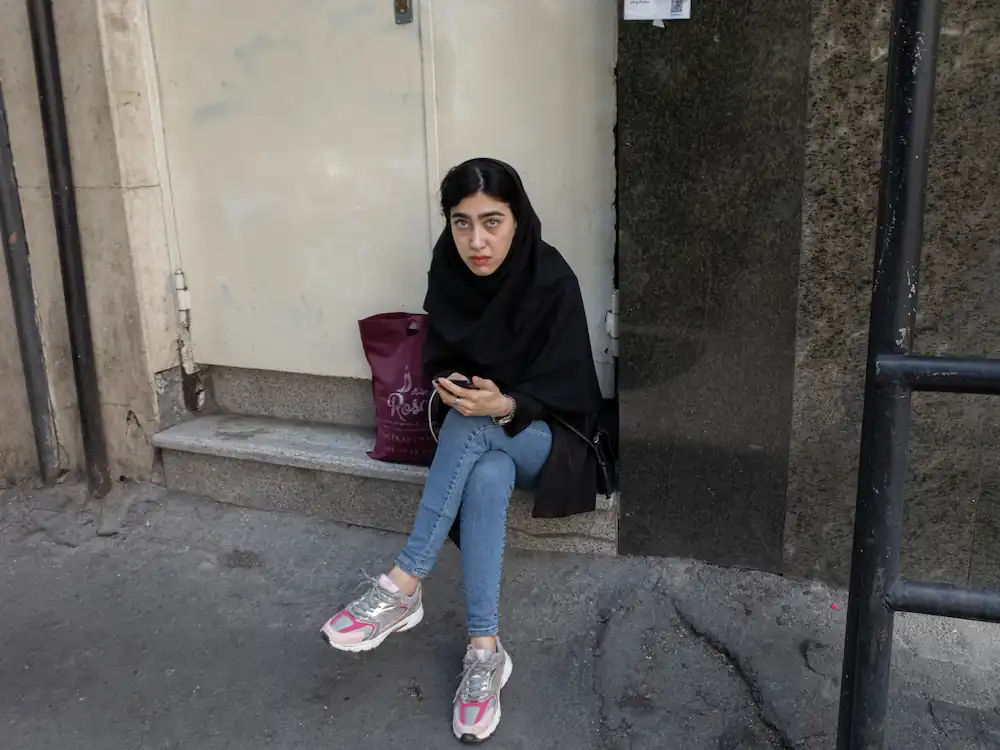 A girl siting in the steps and working on her cellphone