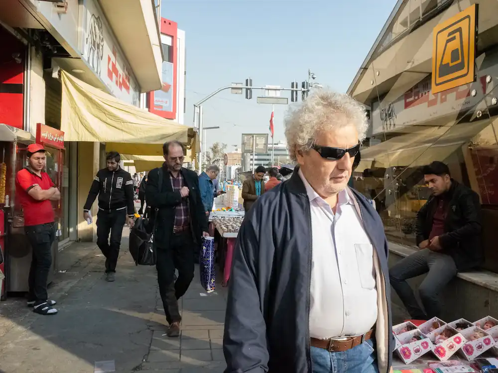 A man looking to a camera passing a sidewalk